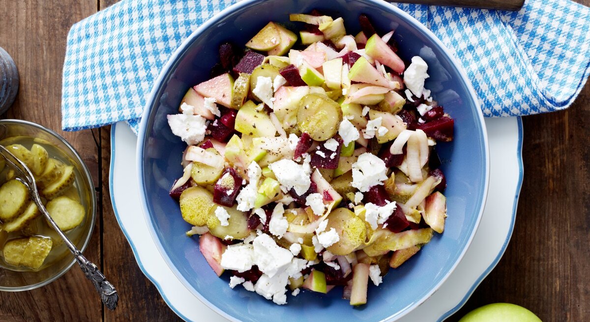 Rote-Bete-Salat mit Schafskäse, Apfelstücken und sauren Gurken, serviert in einer großen Schale auf einem Küchentuch. 