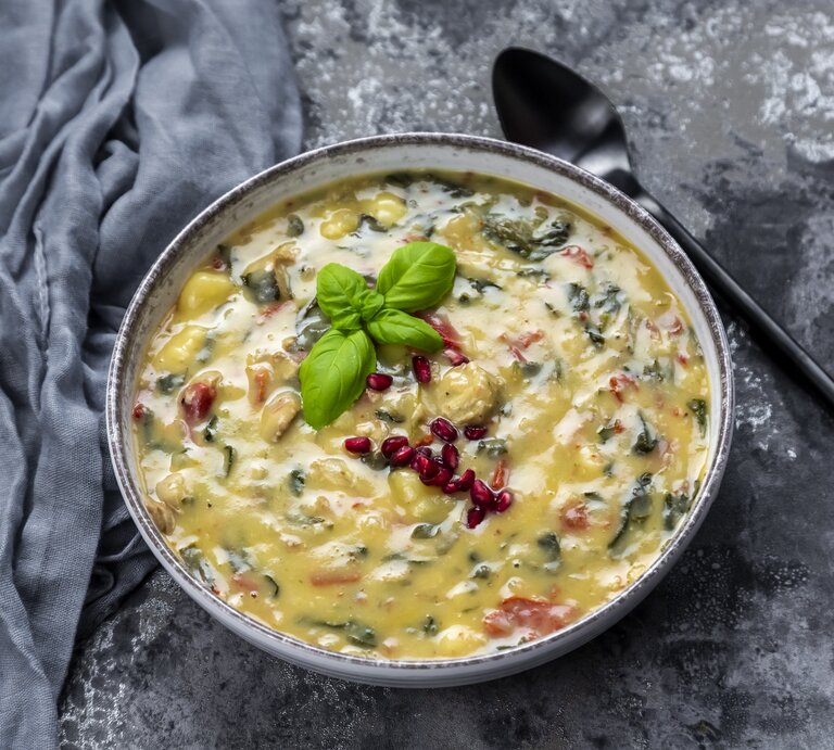 Eine Suppenschüssel mit Gnocchi-Spinat-Suppe auf grauem Hintergrund. | © Getty Images/lacaosa
