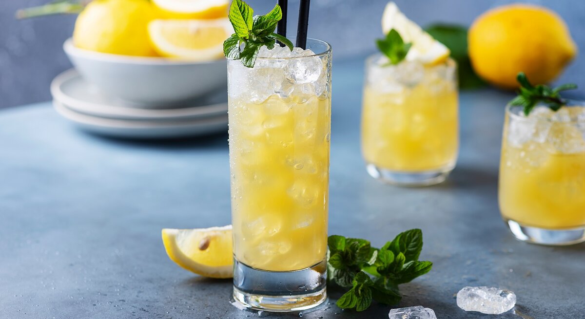 Ein Glas mit Lillet Lemon vor einem grau-blauen Hintergrund.