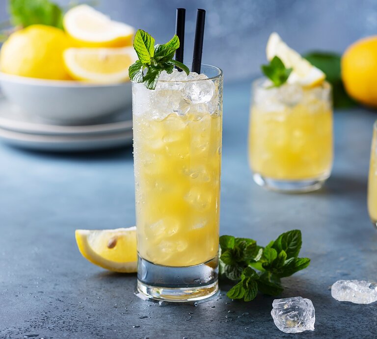 Ein Glas mit Lillet Lemon vor einem grau-blauen Hintergrund. | © Shutterstock/Oxana Denezhkina