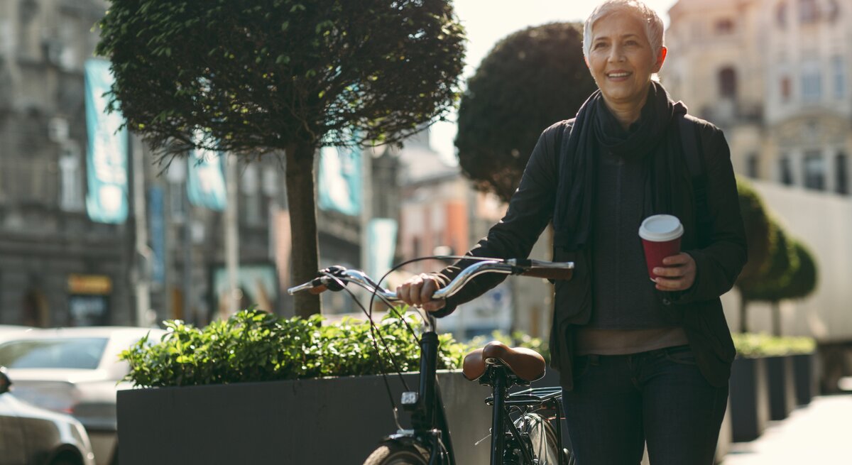 Frau mit Kaffee auf Fahrrad
