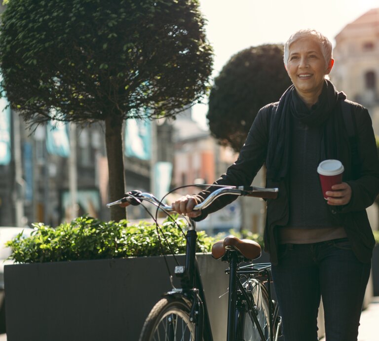 Frau mit Kaffee auf Fahrrad | © iStock/vgajic