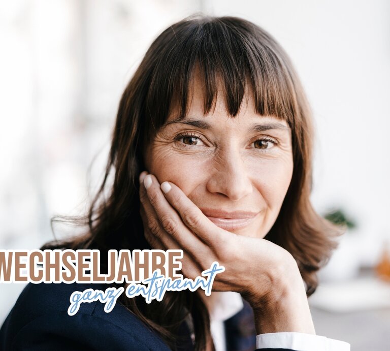 Ein Portrait einer lächelnden Frau mittleren Alters mit schulterlangem braunem Haar. Sie hat ihre Hand liebevoll an ihre Wange gelegt und blickt entspannt in die Kamera. Ihr freundliches Lächeln und ihre sanften Gesichtszüge vermitteln ein Gefühl von Gelassenheit und Zufriedenheit. Am unteren Bildrand steht in stilisierter Schrift: "WECHSELJAHRE ganz entspannt". Der Hintergrund ist hell und unscharf, was den Fokus auf die Person verstärkt. Das Bild strahlt Wärme und Positivität aus. | © GettyImages/Westend61