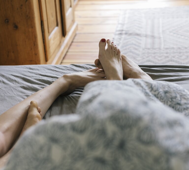 Füße von Mann und Frau im Bett zu sehen | © Getty Images /	Willie B. Thomas