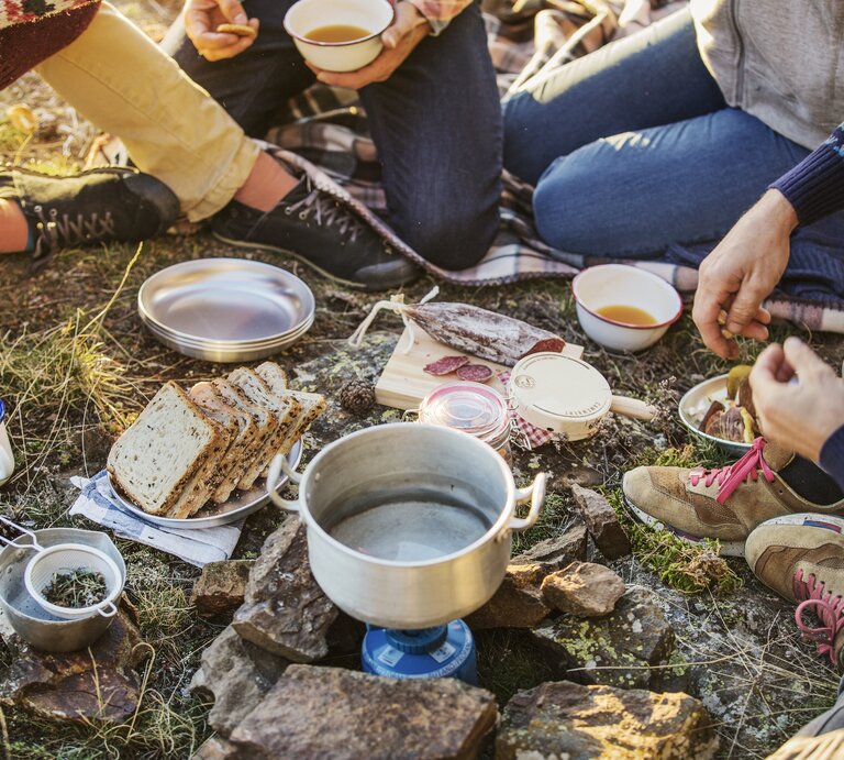 Eine Gruppe an Freunden frühstücken beim Camping-Ausflug. | © Getty Images/Morsa Images