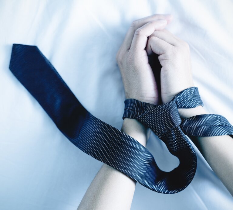 Mit einem Seidenruch gefesselte Handgelenke eines Mannes. | © iStock.com 7 / nito100