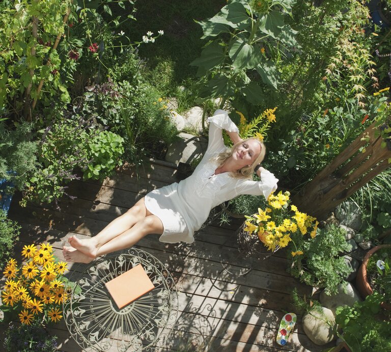 Frau liegt entspannt im Garten.  | © Getty Images/Hans Huber