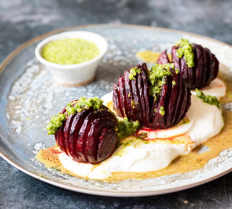 Ein Teller mit drei Hasselback-Beten, grünem Dressing und Joghurt. | © Adobe Stock/ Magdalena Bujak