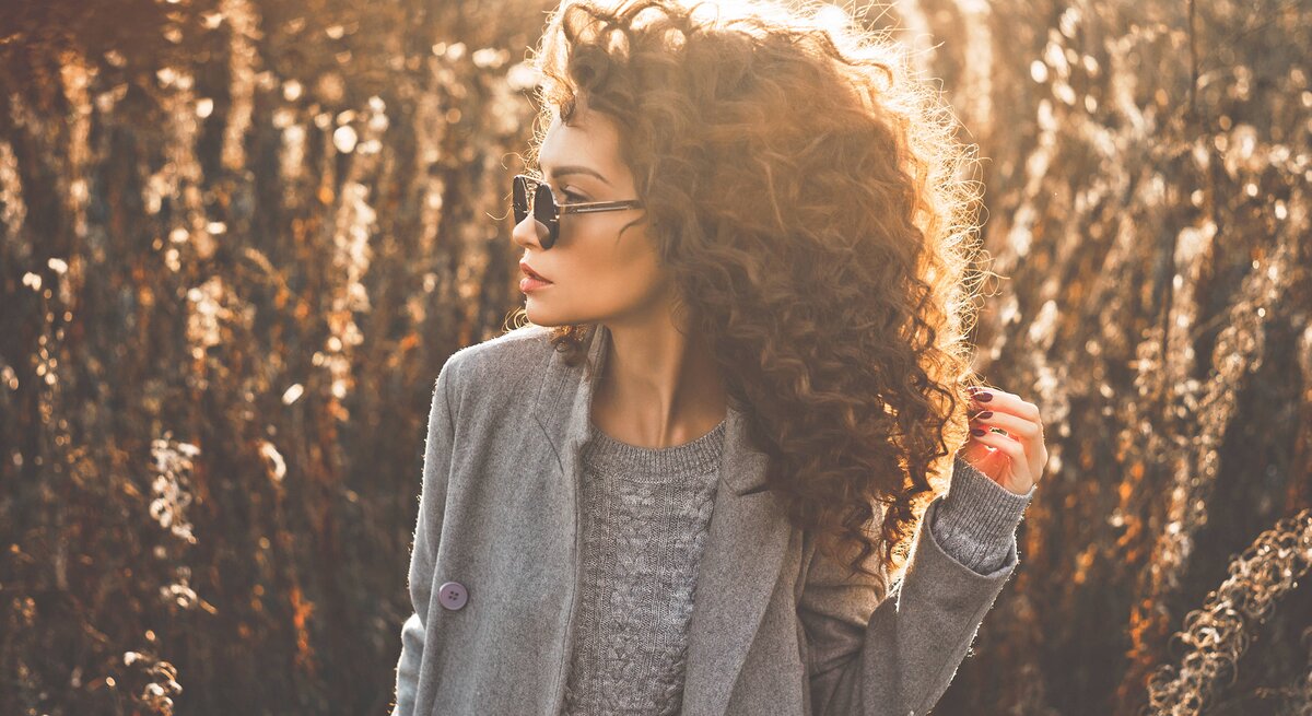 Frau mit schönen, definierten Locken steht auf einem Feld. 
