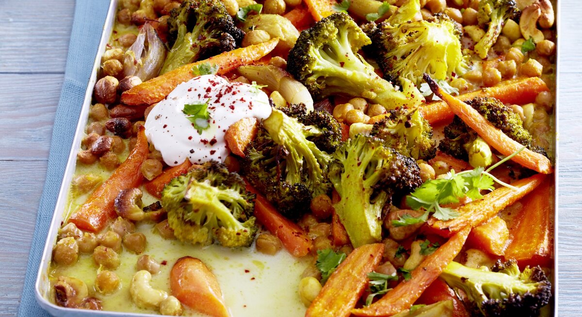 Gemüsecurry vom Blech aus Brokkoli, Kichererbsen,  und feinen Möhren, serviert mit würzigem Joghurt und Chiliflocken. 