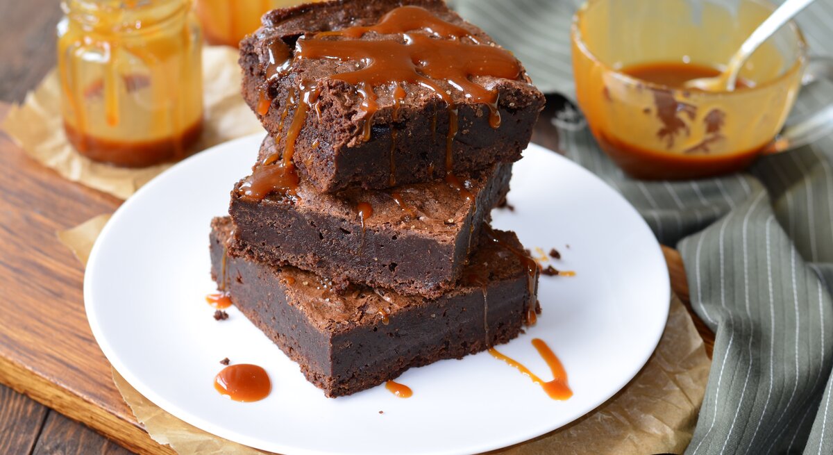 Ein Teller mit Salzkaramell-Brownies auf einem Holzbrett.