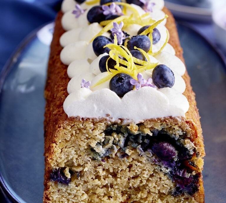 Auf einem Teller steht ein Heidelbeer-Haferflocken-Kuchen. Er ist mit Sahne und Blaubeeren dekoriert. | © EAT CLUB / Isabell Triemer