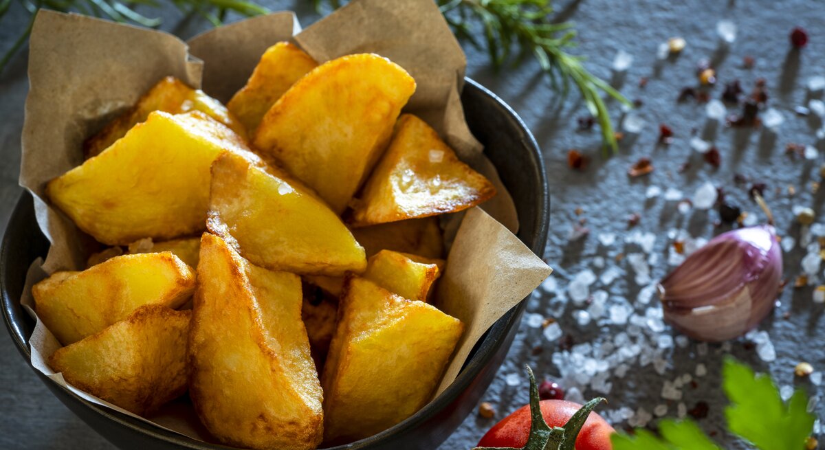 Krosse Kartoffeln in einer Schale umgeben von Gewürzen.