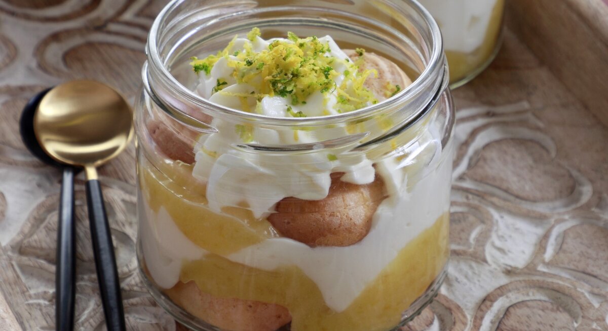 Ein Glas Zitronen-Tiramisu mit Zitronenzeste und Limettenabrieb dekoriert.
