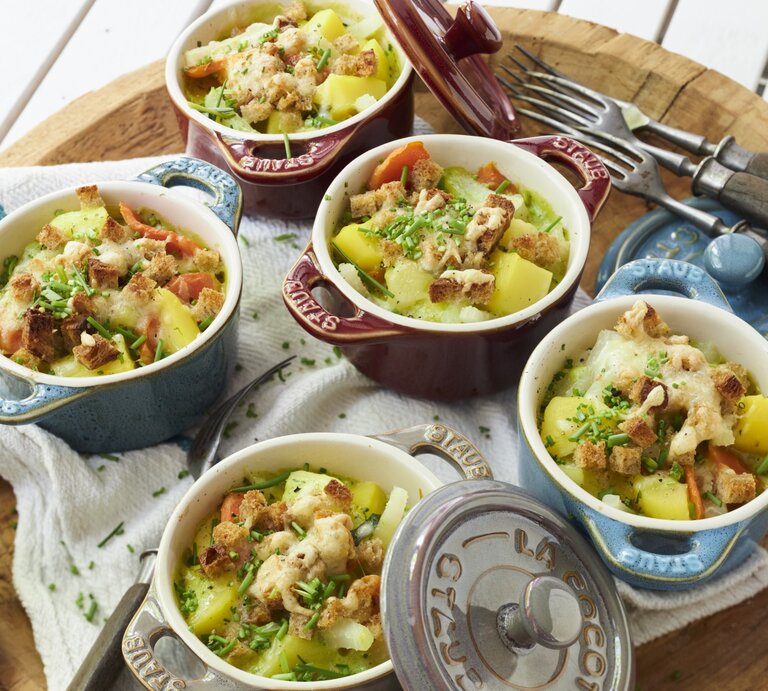 Kräuter-Kartoffel-Töpfchen in kleinen Ofenförmchen, mit Käse überbacken und frischem Schnittlauch serviert auf einem rustikalen Holzbrett.  | © StockFood / StockFood Studios / Brachat, Oliver