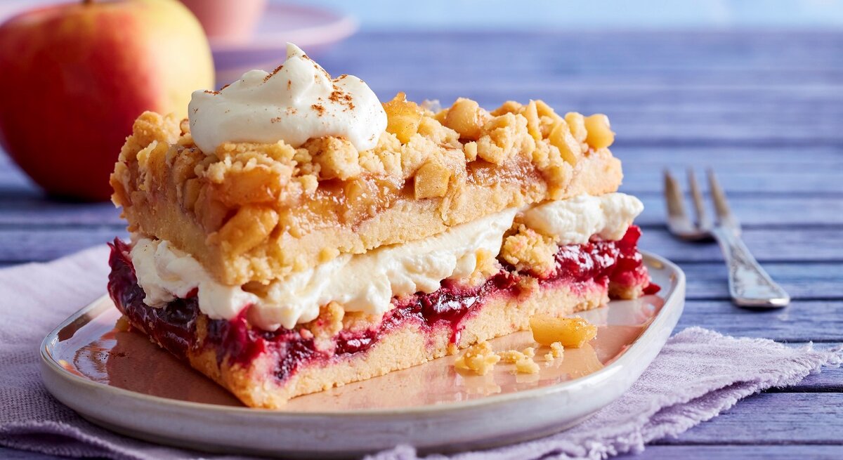Auf einem Teller steht ein Stück Prasselkuchen mit Vanille-Mascarpone-Creme. Es ist mit einem Tuff Creme verfeinert.