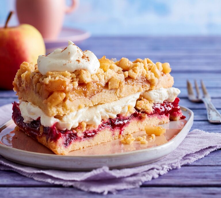 Auf einem Teller steht ein Stück Prasselkuchen mit Vanille-Mascarpone-Creme. Es ist mit einem Tuff Creme verfeinert. | © EAT CLUB / Isabell Triemer