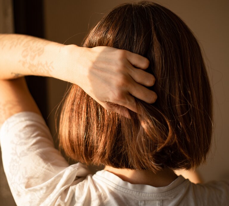 Eine Frau fasst sich in die Haare. | © Getty Images/Photographer, Basak Gurbuz Derman