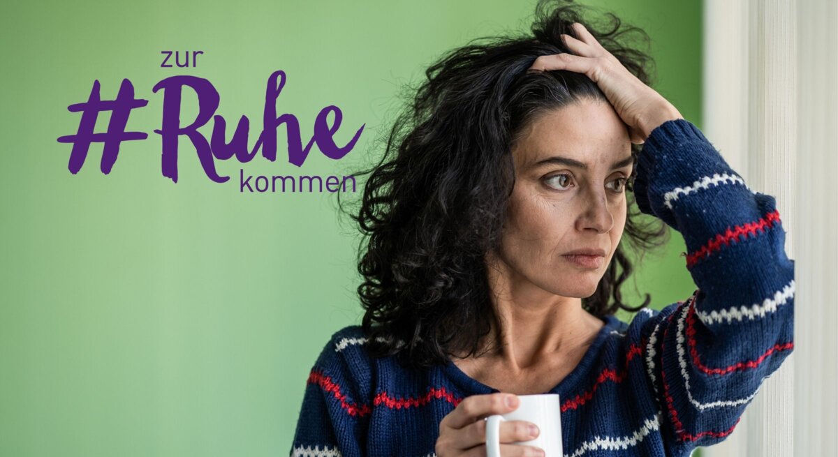 Eine nachdenkliche Frau mit dunklem Haar hält eine Tasse in ihrer Hand und blickt in die Ferne, während sie ihre andere Hand an ihren Kopf legt. Sie trägt einen gestreiften Pullover und steht in einem Raum mit grünen Wänden. Neben ihrem Kopf steht der Text "zur #Ruhe kommen" in lila Schrift, was auf einen thematischen Fokus auf Entspannung oder Selbstfürsorge hinweist.