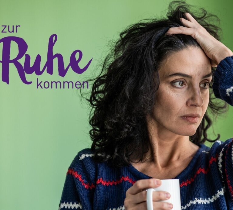 Eine nachdenkliche Frau mit dunklem Haar hält eine Tasse in ihrer Hand und blickt in die Ferne, während sie ihre andere Hand an ihren Kopf legt. Sie trägt einen gestreiften Pullover und steht in einem Raum mit grünen Wänden. Neben ihrem Kopf steht der Text "zur #Ruhe kommen" in lila Schrift, was auf einen thematischen Fokus auf Entspannung oder Selbstfürsorge hinweist. | © iStock.com/valentinrussanov