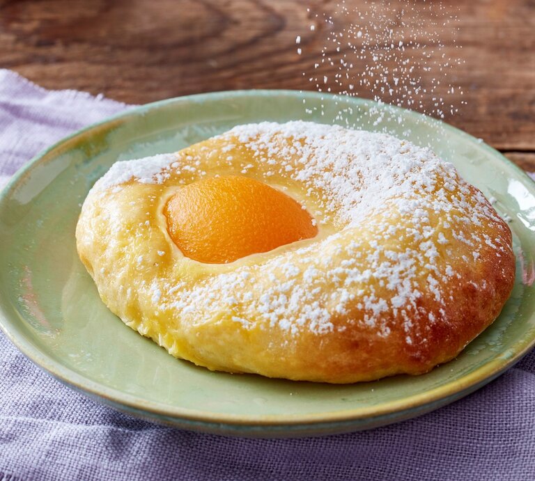 Auf einem Teller liegt eines der süßen Spiegeleier. Es ist mit Puderzucker bestreut und goldbraun gebacken. | © EAT CLUB / Isabell Triemer
