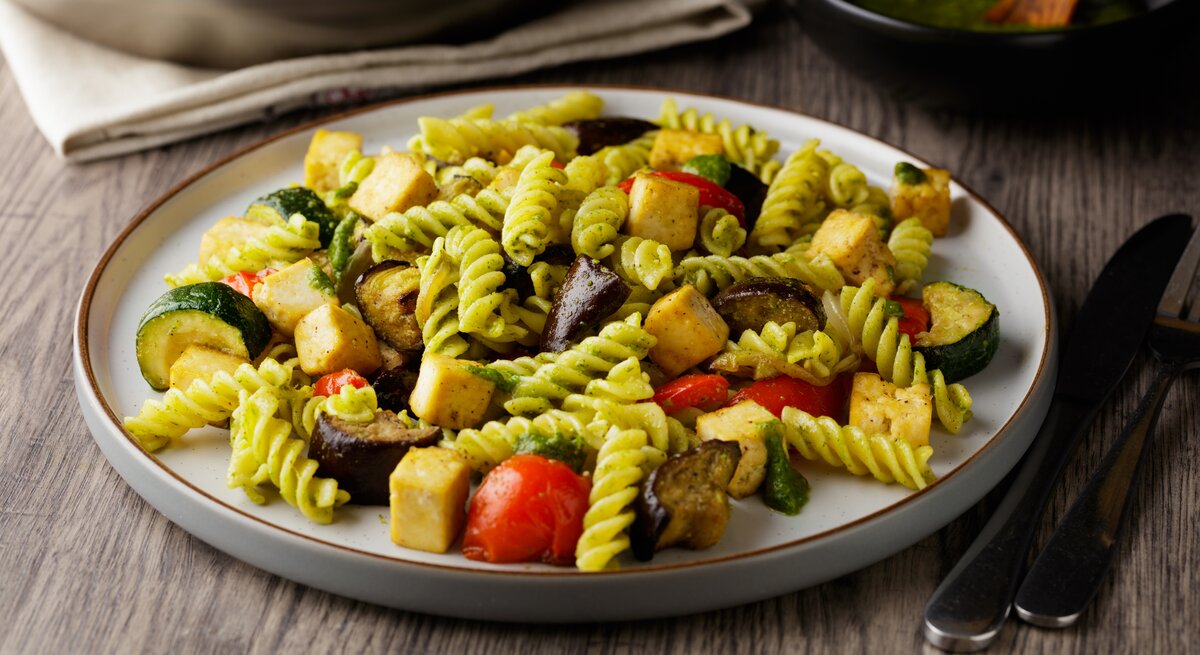 Pasta mit Pesto, gegrilltem Gemüse und Tofu auf weißem Teller