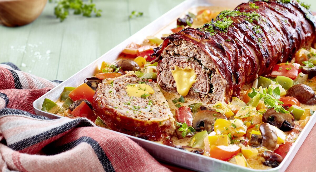 Gefüllter Hackbraten auf Paprika-Rahm auf Teller angerichtet.