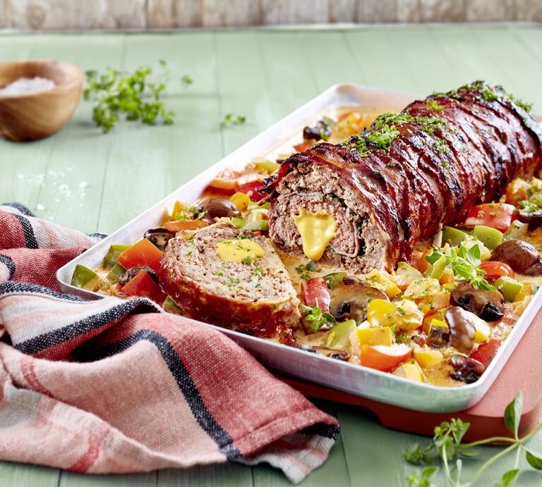 Gefüllter Hackbraten auf Paprika-Rahm auf Teller angerichtet. | © EAT CLUB/Isabell Triemer