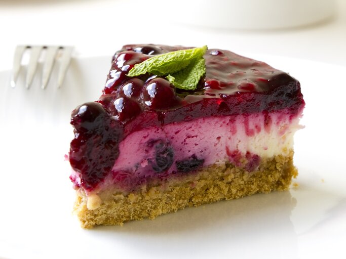 Angeschnittenes Stück Lillet-Käsekuchen auf weißem Untergrund. Daneben liegt eine Gabel. | © Getty Images/Synergee