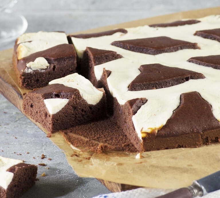 Auf einem Backpapier liegt ein Kuhflecken-Kuchen. Er hat ein geflecktes Muster aus Schokolade und Vanille. | © StockFood / Tre Torri