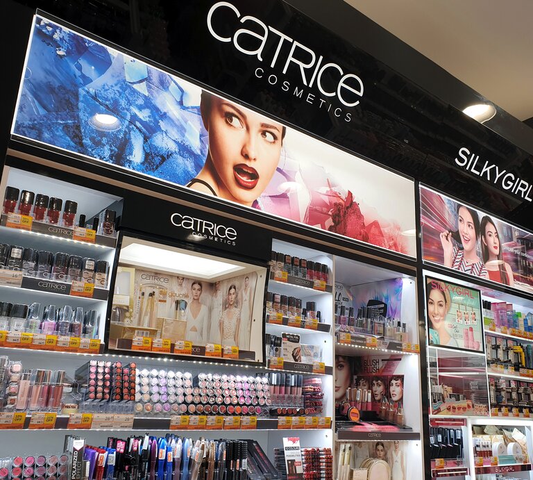 Kosmetikladen-Display, das eine Vielzahl von Produkten der Marken Catrice Cosmetics und SilkyGirl präsentiert. Die Produkte sind übersichtlich auf mehreren Regalen angeordnet. | © Shutterstock/TY Lim