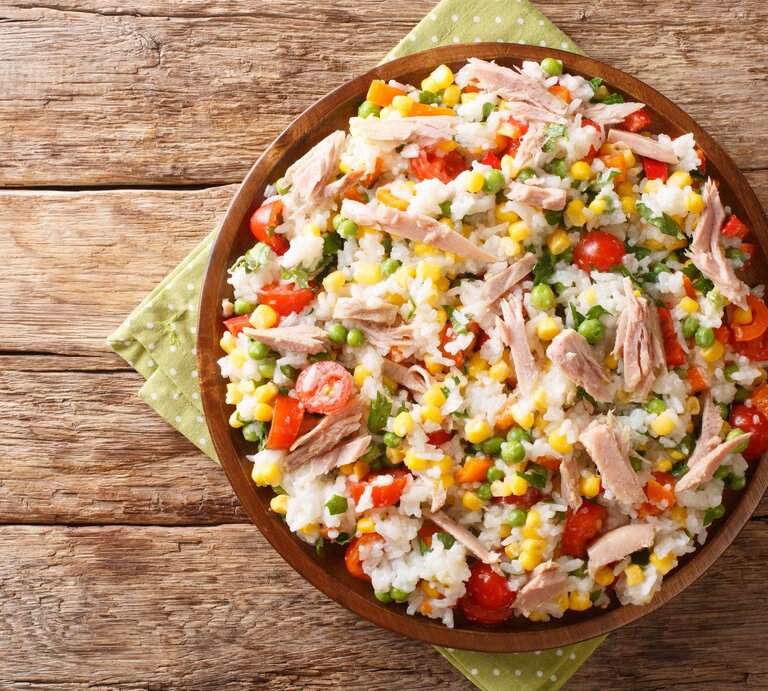 Reissalat mit Thunfisch und Gemüse in brauner Tonschale auf Papierserviette auf Holztisch. Aufnahme aus der Vogelperspektive. | © Getty Images / ALLEKO