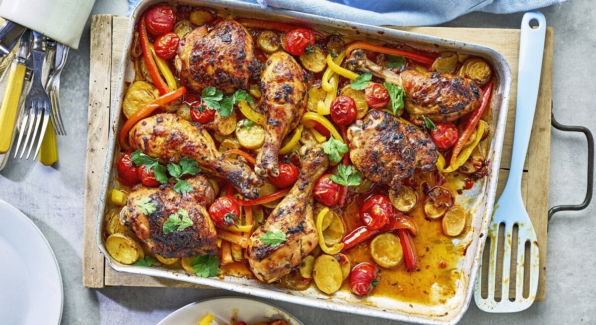 In einer Ofenform ist eine Portion Piri-Piri-Hähnchen vom Blech angerichtet. Dazu gibt es Paprika.