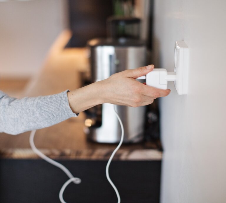 Eine Frau steckt einen Stecker in eine Steckdose. | © Gettyimages / Maskot