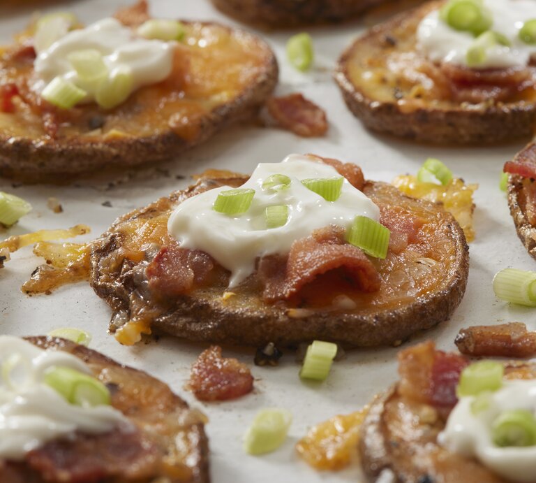 Doppelt gebackenen Kartoffeln mit Schmand und Speck auf weißer Oberfläche.  | © Getty Images/LauriPatterson