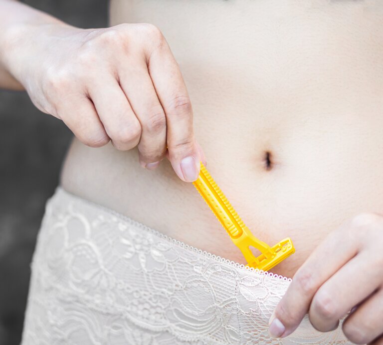 Frau mit Rasierer am Intimbereich in der Hand.jpg | © Getty Images / Doucefleur