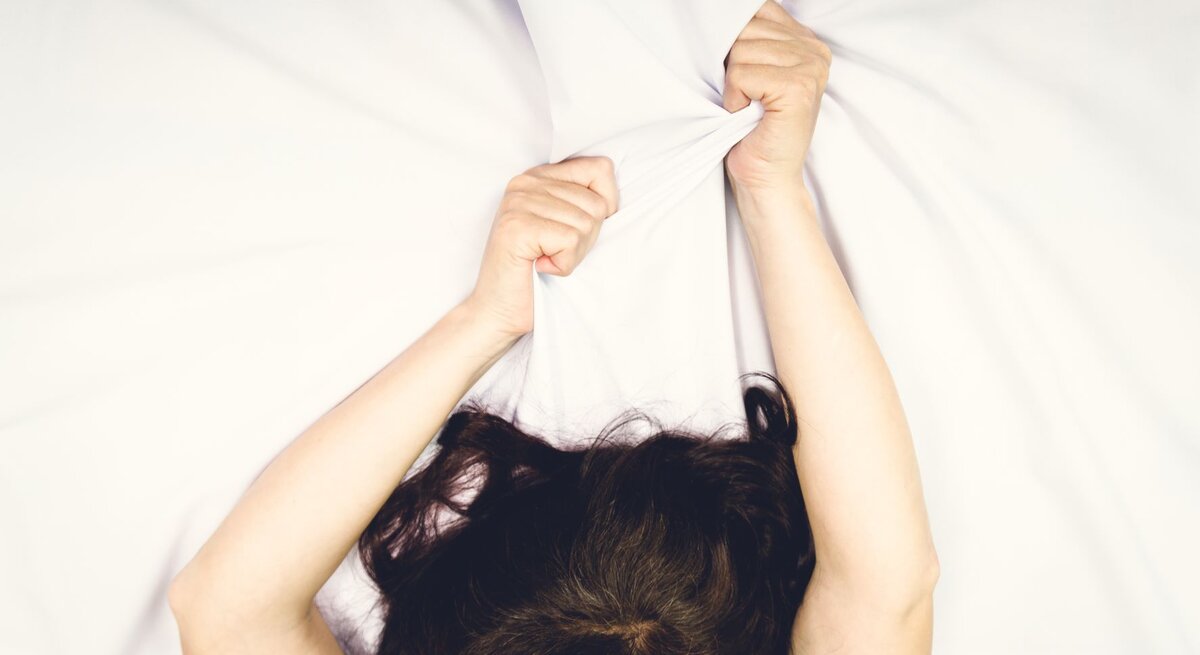 Arme von Frau im Bett, die sie erregt in die Höhe streckt