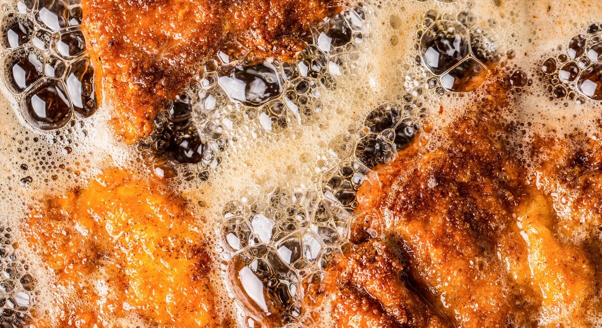 Brutzelnde Schnitzel in einer Pfanne mit heißem Fett.