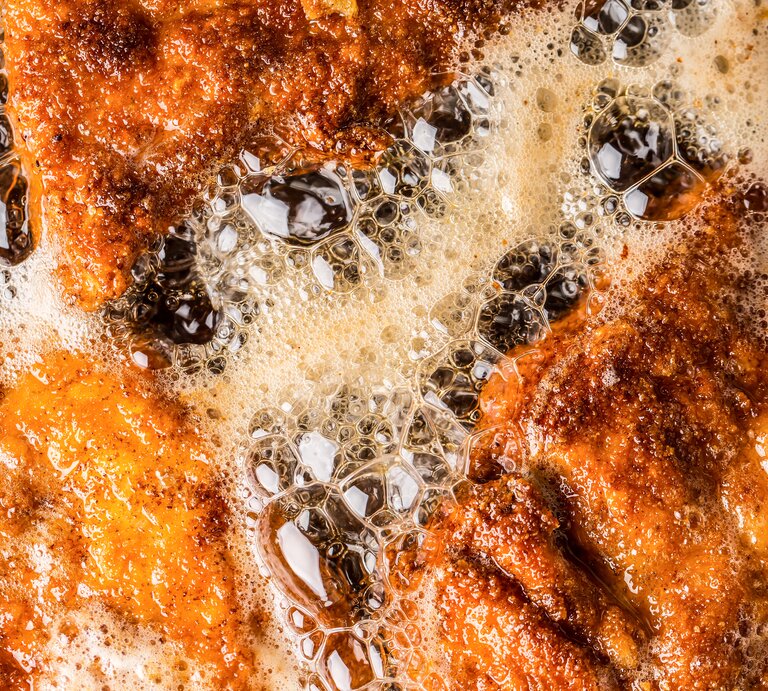 Brutzelnde Schnitzel in einer Pfanne mit heißem Fett. | © GettyImages/MarianVejcik
