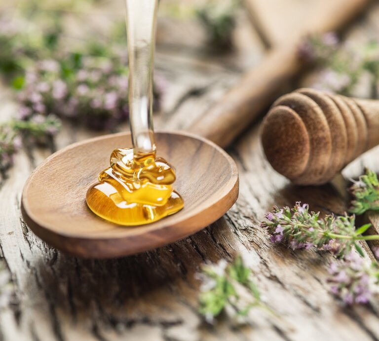 Auf einen Holzlöffel wird Hongig verteilt. | © ©iStock/ValentynVolkov