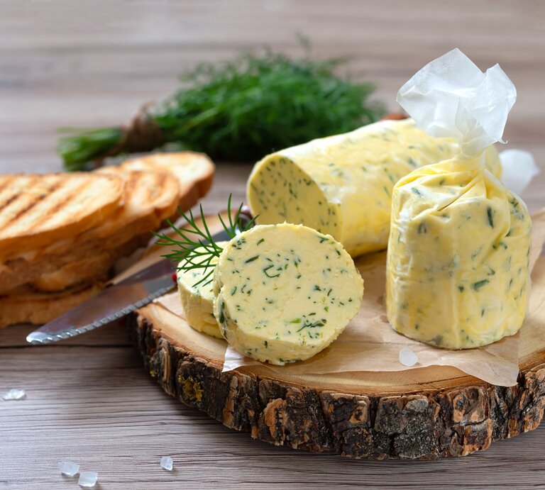 Eine Rolle mit Dill-Zitronenbutter auf einer Baumscheibe. | © Shutterstock/Iaroshenko Maryna