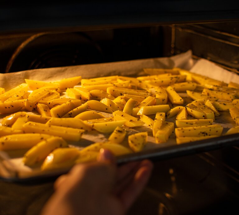 Ein Backblech mit Pommes im Ofen. | © GettyImages/ Marta Dabrowska