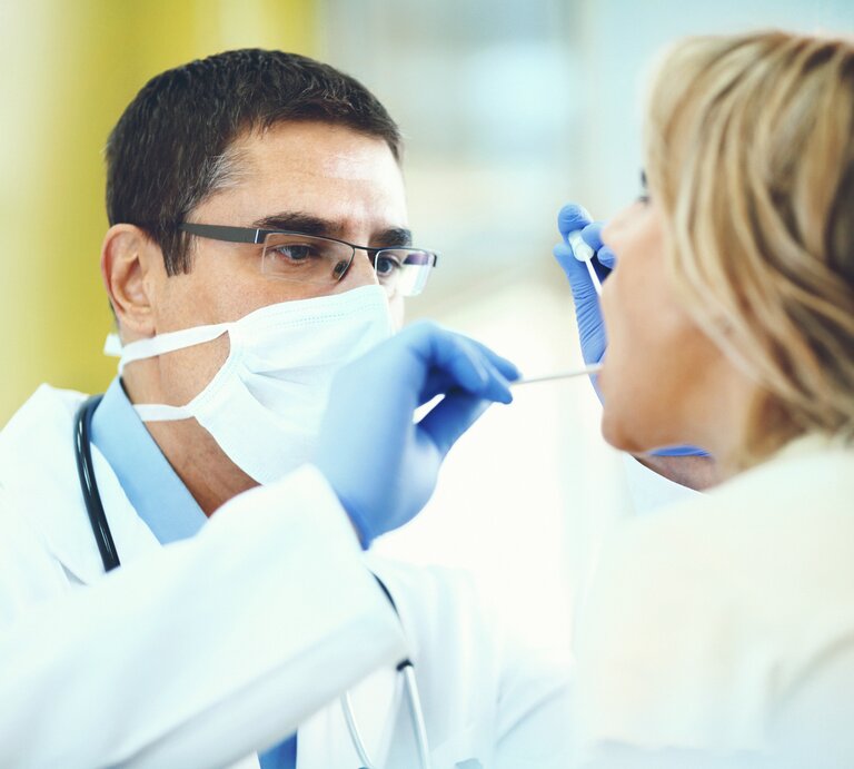 Arzt untersucht Frau mit Halsschmerzen | © Getty Images/gilaxia