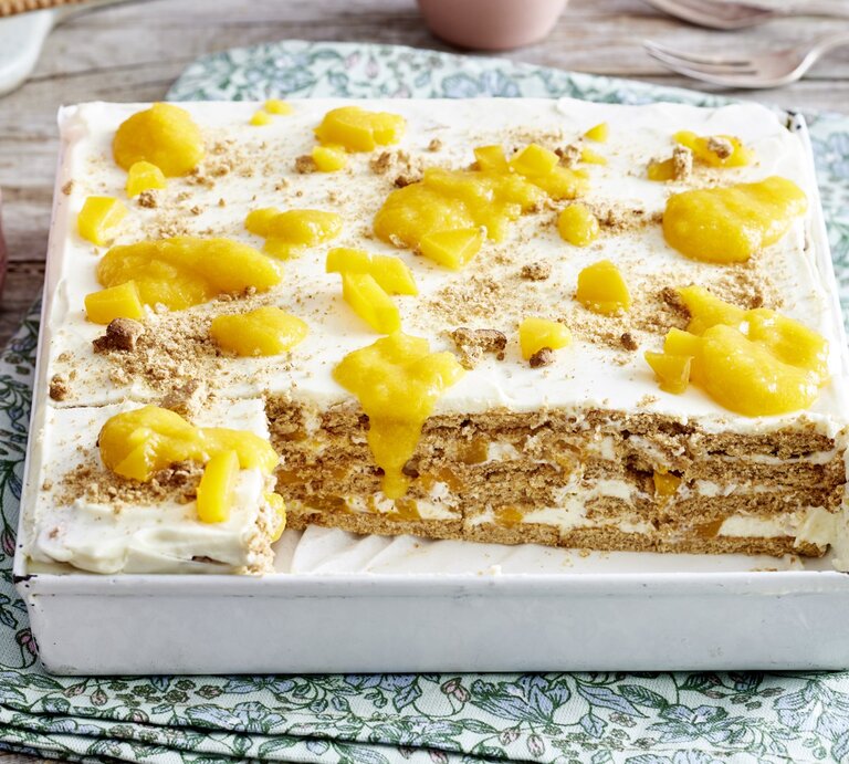 In einer Form ist ein Knusperkeks-Pfirsichschnitten angerichtet. Er ist in Blechform und mit frischen Pfirsichen belegt. | © EAT CLUB / Isabell Triemer