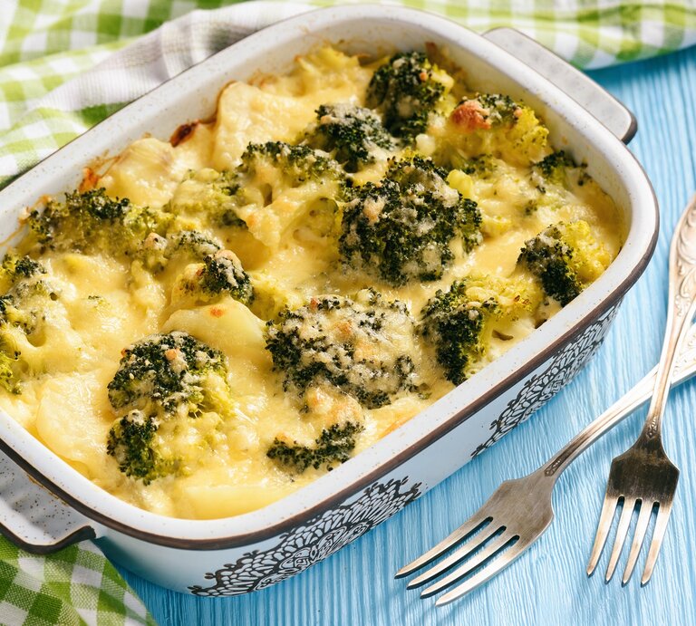 Eine Ofenform mit Kohlrabi-Brokkoli-Auflauf, überbacken mit Käse, daneben liegen ein Geschirrtuch und zwei Gabeln. | © Adobe Stock/ O.B.