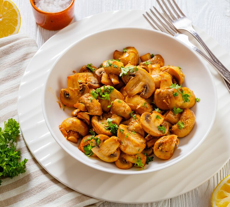 Spanische Knoblauch-Champignons in weißer Schale auf weißem Holz.  | © Getty Images/ from_my_point_of_view