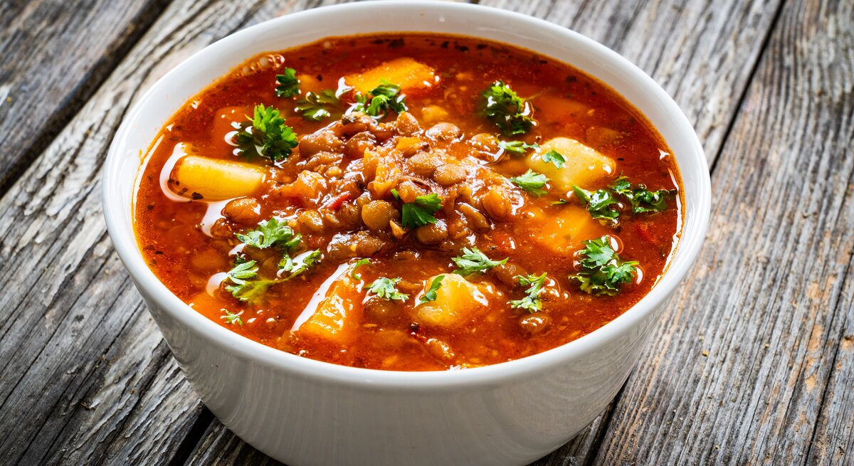 Eine Schüssel Kokos-Kichererbsensuppe mit Kartoffeln, Tomaten und gehacktem Koriander.
