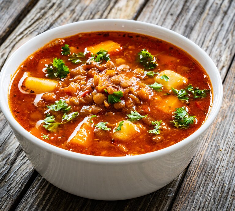 Eine Schüssel Kokos-Kichererbsensuppe mit Kartoffeln, Tomaten und gehacktem Koriander. | © Shutterstock/ Jacek Chabraszewski