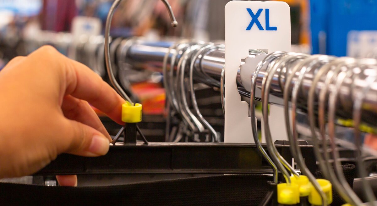 Kleiderbügel auf einer Kleiderstange, ein XL-Zeichen ist an der Stange angebracht