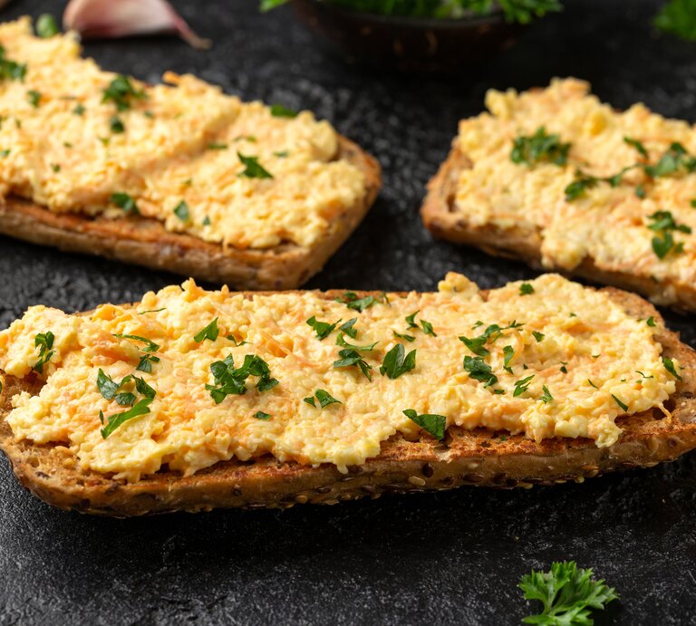drei brote mit einem Käse-Karotten-Aufstrich liegen auf einem Tisch. | © Getty Images / DronG